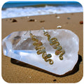 Copper and gemstone earrings on a clear crystal with a beach background