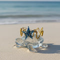 Glass turtle figurine with starfish bracelet and anchors on a sandy beach