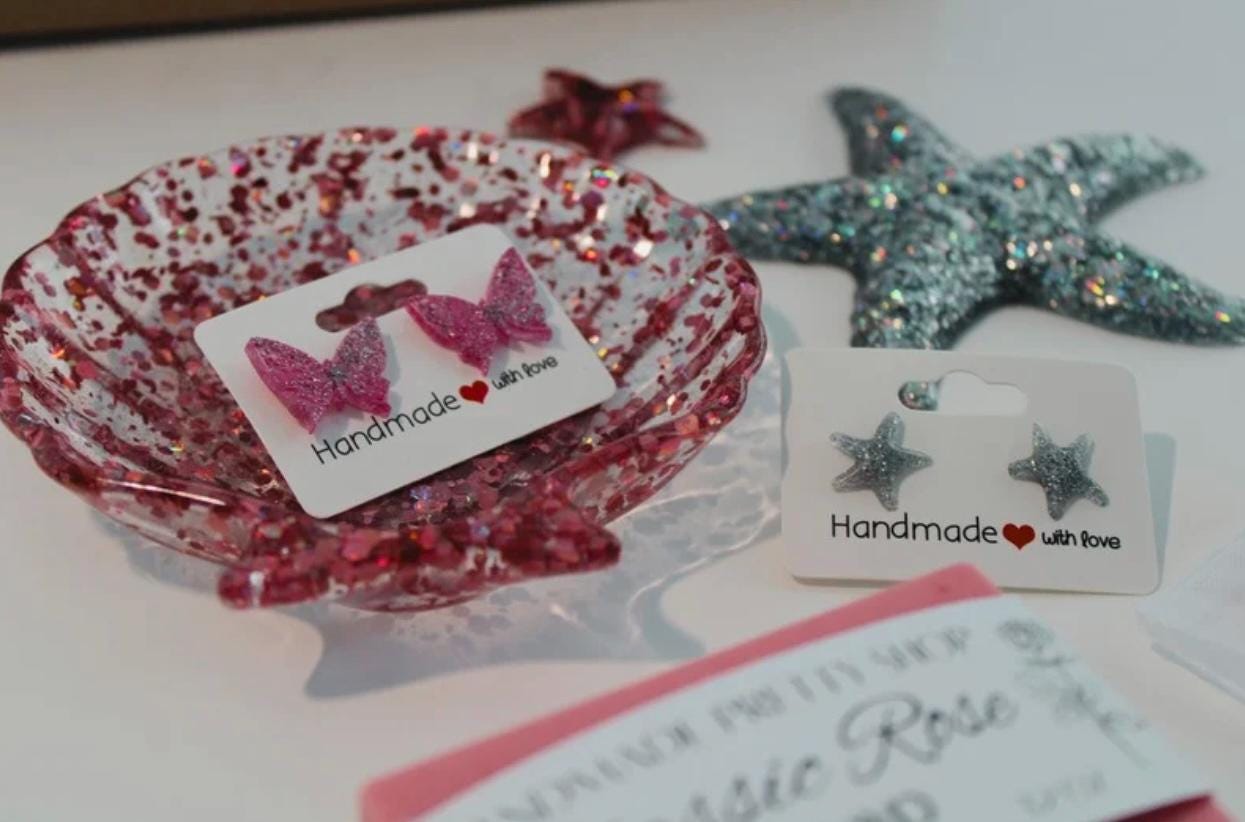 Handmade jewelry items including a seashell resin dish, two stud earrings, resin starfish, and a handmade soap bar.