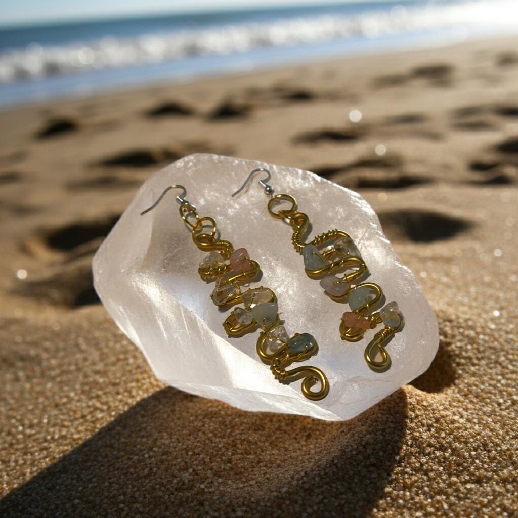 Copper and multicolored stone earrings on a clear stone with a beach background
