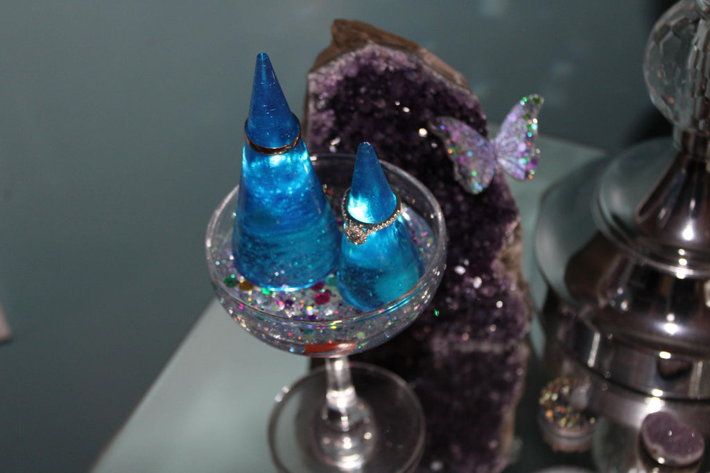 Decorative blue jewelry display cones in a glass with a crystal in the background