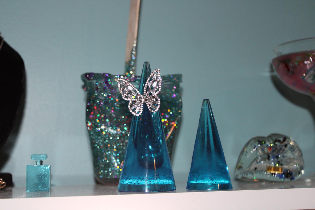 Blue resin ring holders with decorative elements on a reflective surface