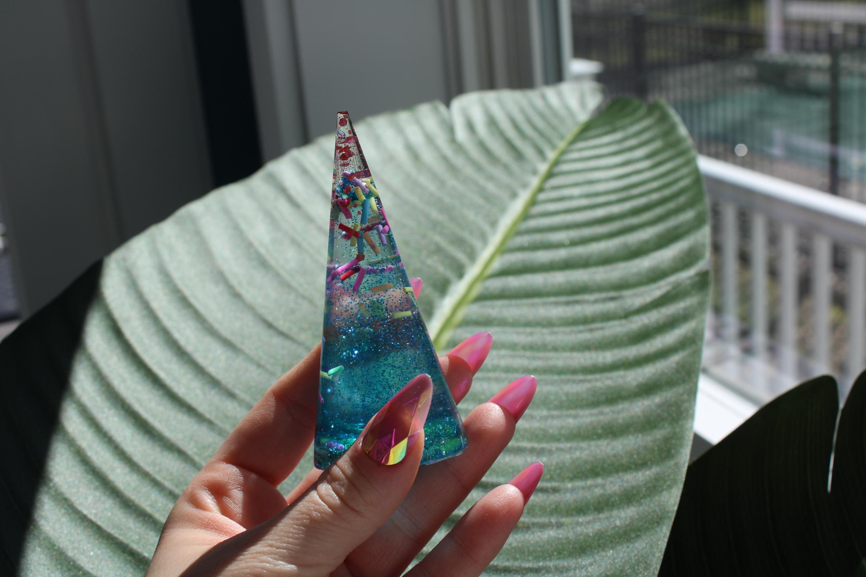 Sprinkle design ring holder display cone held by a hand against a leafy background