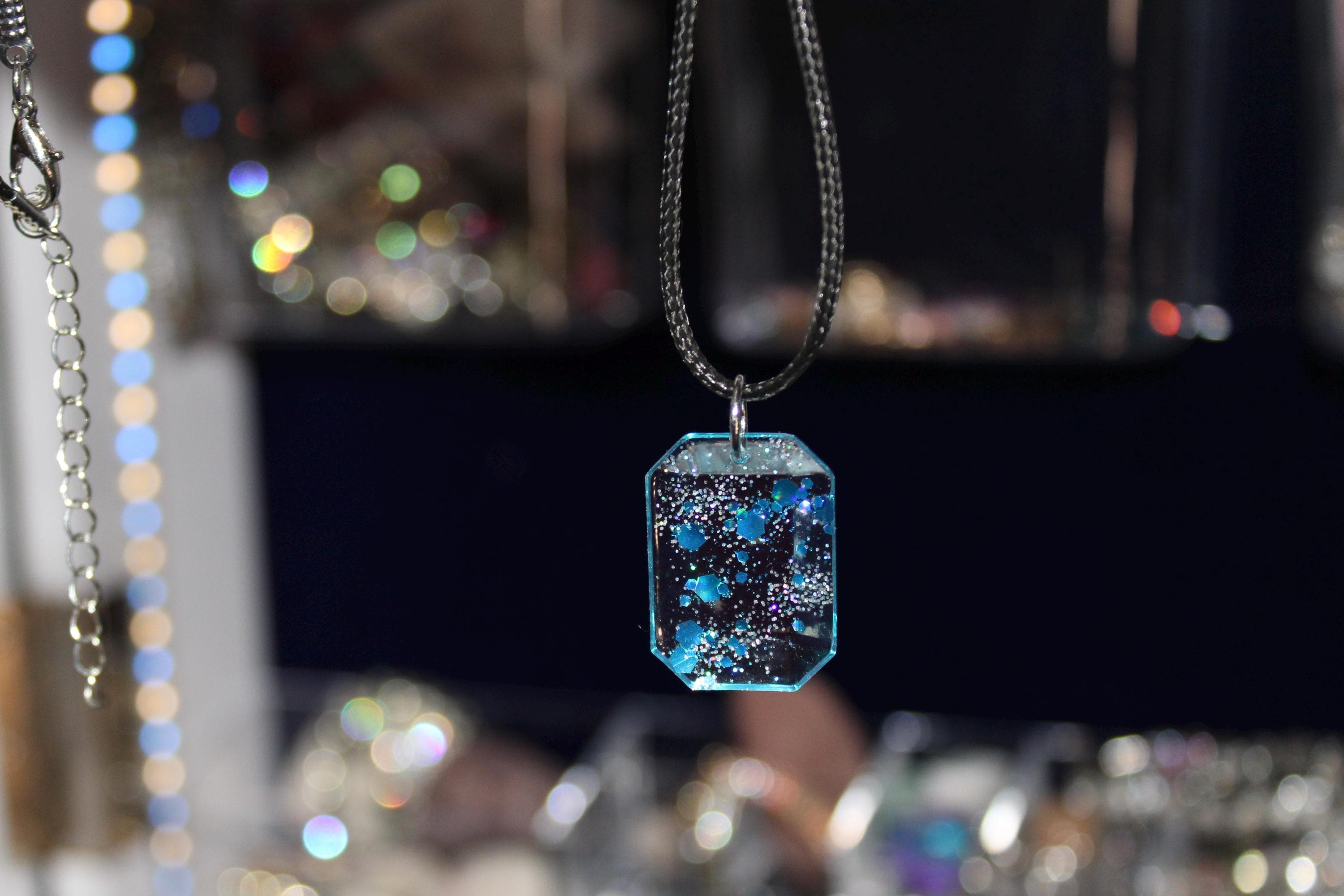 Necklace with a blue and purple pendant against a blurred jewelry store background