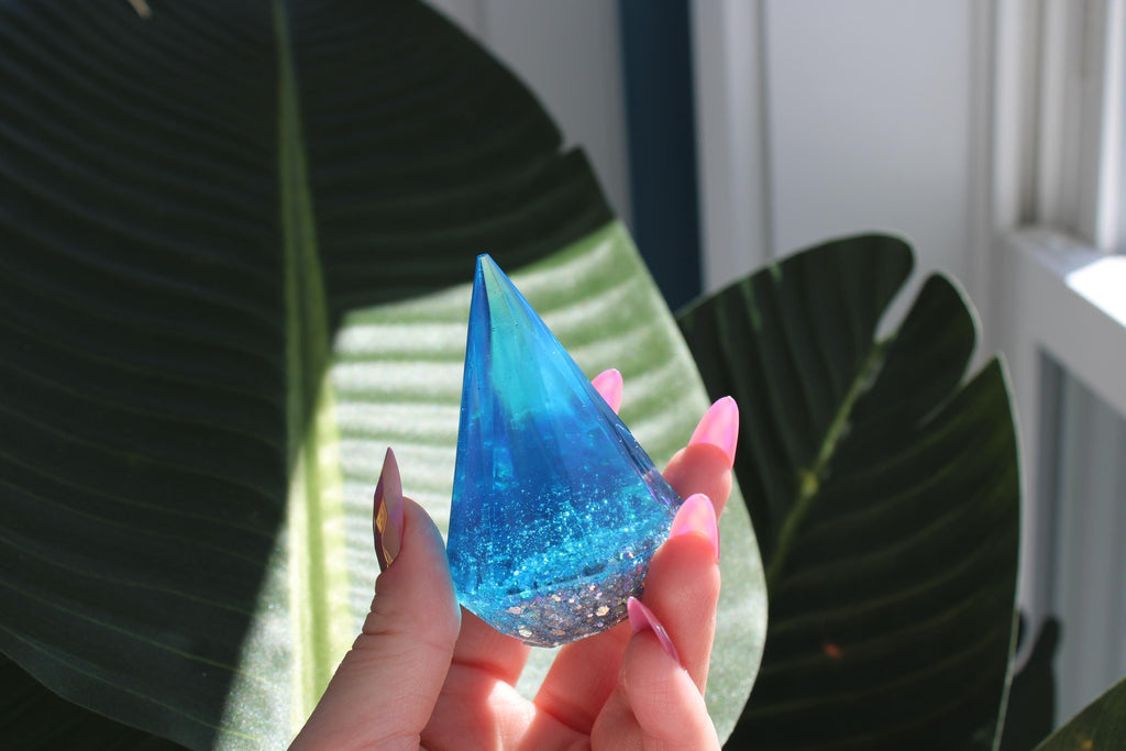 Hand holding a blue ring holder with leaves in the background