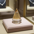 Diamond ring on a gold and resin display stand in a jewelry store setting.