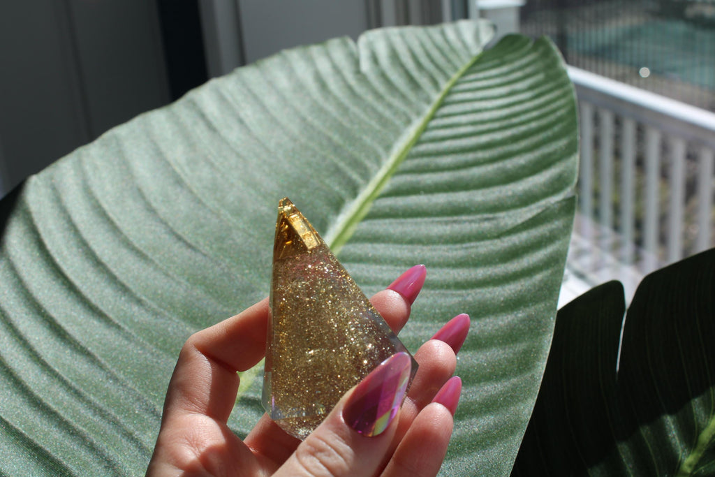 Hand holding a glittery ring holder display with a leaf in the background