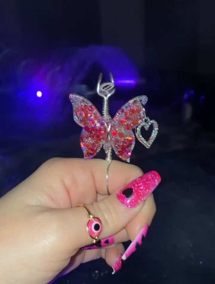 The video shows a hand holding a pink sequin butterfly smoke ring with a faux joint in front of a hot tub.