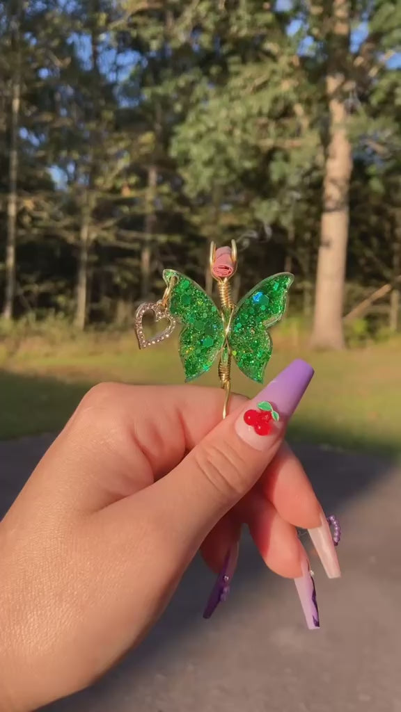Green sequin butterfly lit with a faux joint in a forest setting 