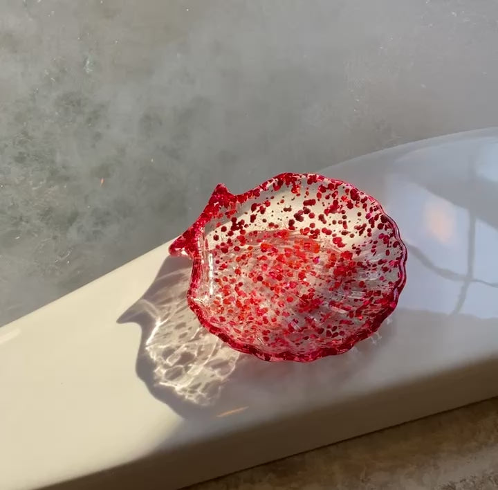Video shows a rose pink sequin seashell soap dish on the edge of a tub