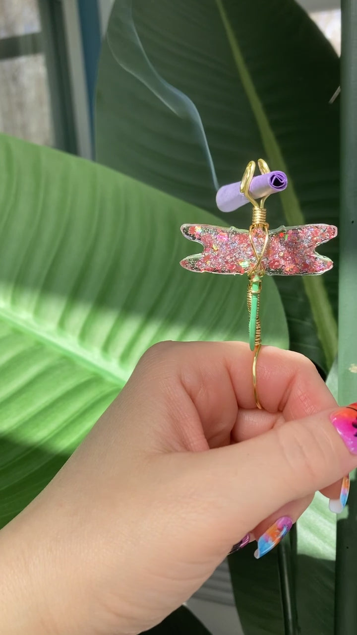 Video shows a pink dragonfly smoke ring held by a manicured hand