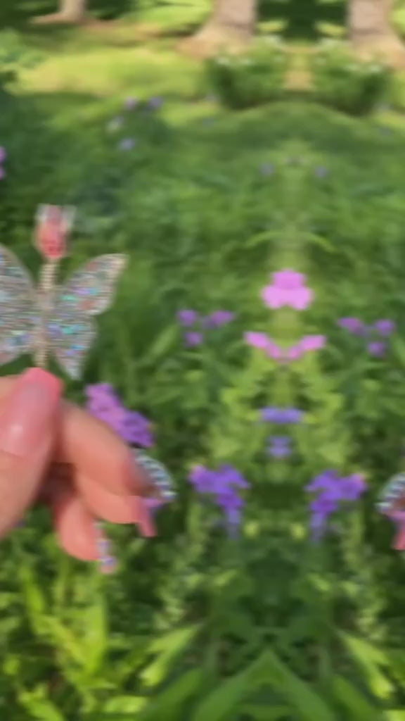 Silver sequin butterfly with a lit faux joint in a field of flowers.