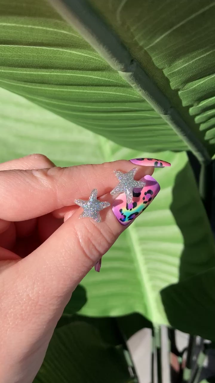 The video shows glitter starfish earrings in a manicured hand