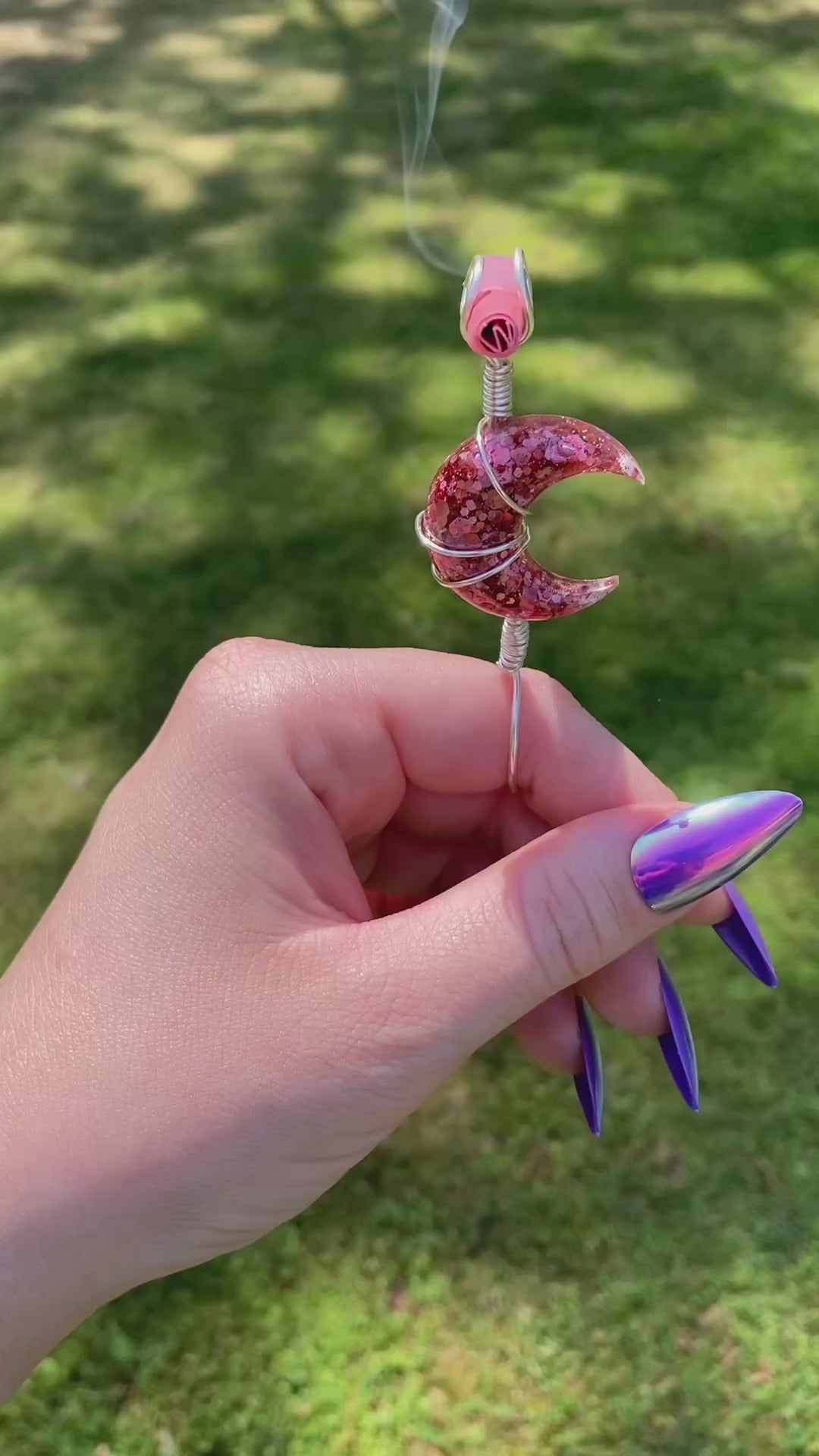Video shows a pink sequin crescent moon smoke ring lit with a faux joint outside 