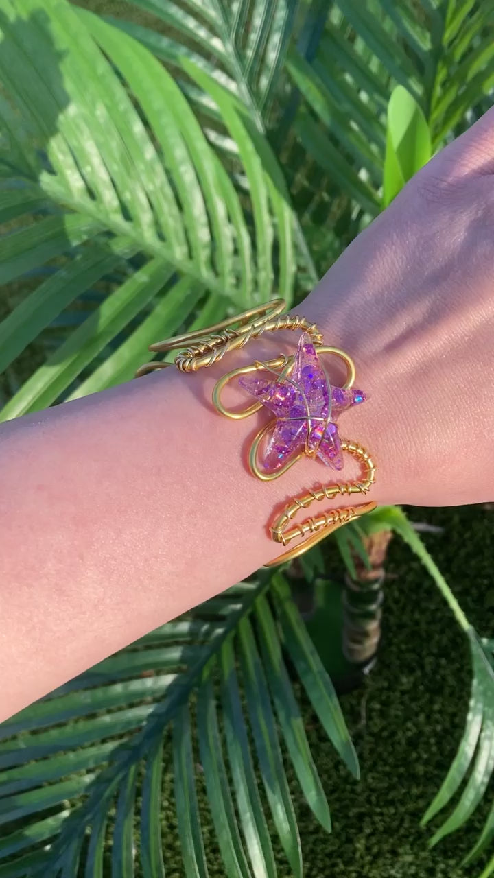 Video shows a purple sequin starfish wire wrapped copper bracelet on an arm in front of a fake plant 