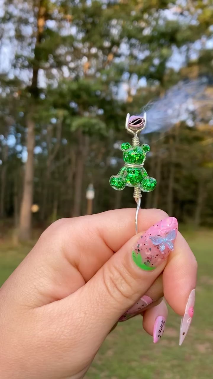 Video shows a green teddy bear smoke ring lit with a faux joint in a nature setting