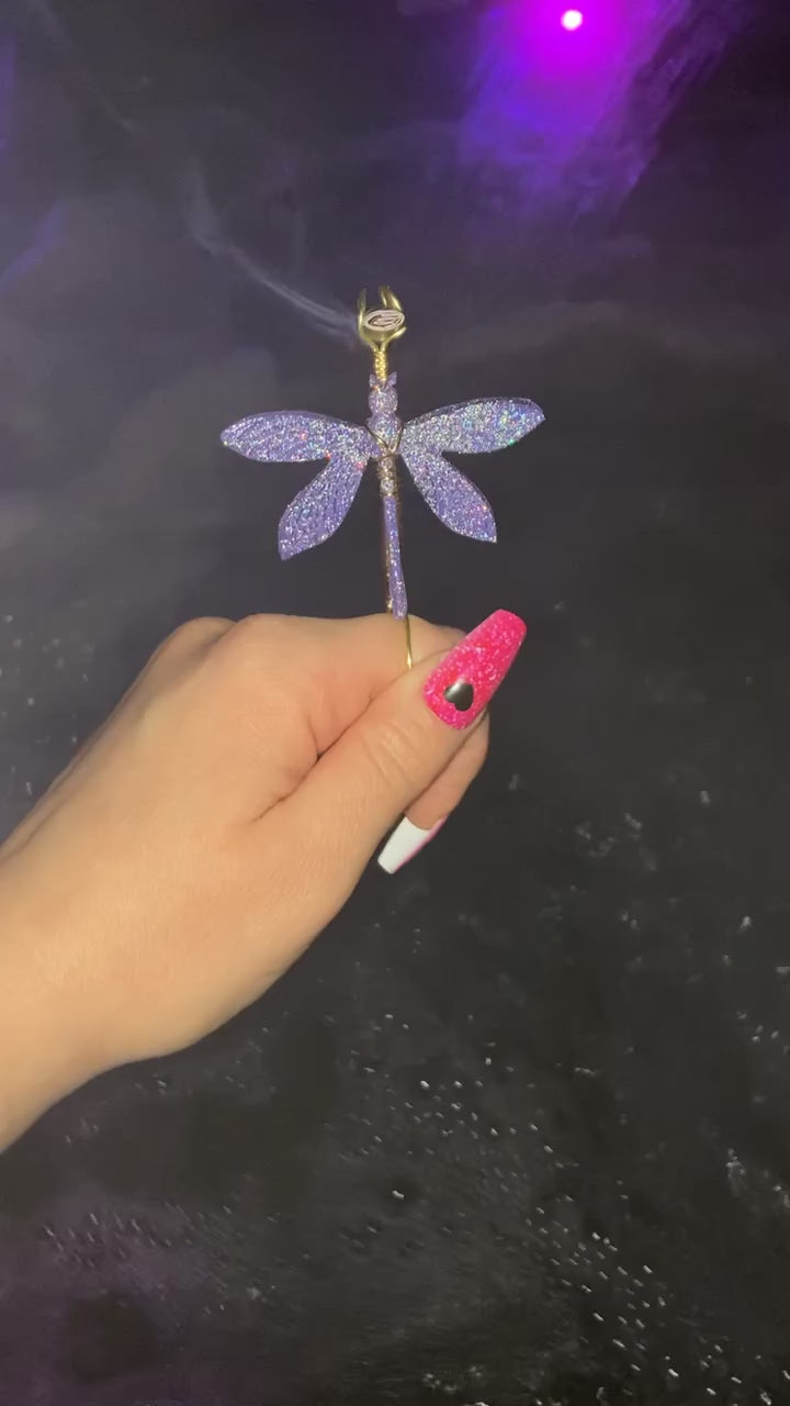 The video shows a purple sparkly dragonfly smoke ring lit with a faux joint.