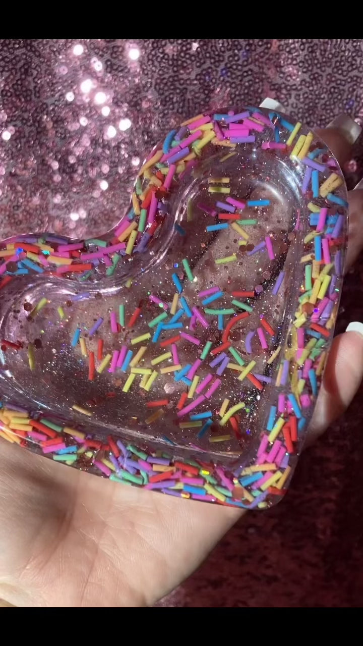 Hand is holding a heart-shaped sprinkle resin handmade ashtray 