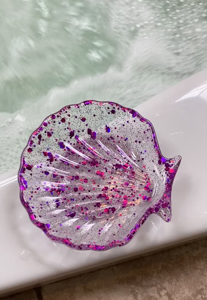 Purple sequin seashell soap dish on the edge of a jacuzzi tub.